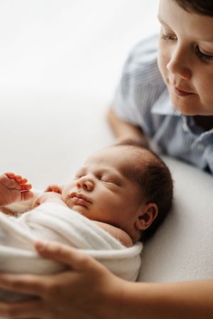 Peaceful sleeping newborn being gently cradled in soft natural window light.