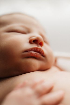 Close-up macro photo of a sleeping baby's lips and nose against soft white bedding.