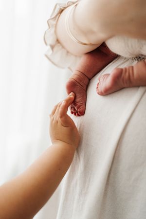 Close up of tiny baby hand holding adult finger in soft natural light.