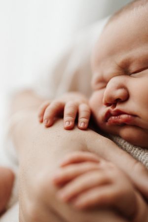 Peaceful sleeping newborn baby with tiny hands in soft focus.
