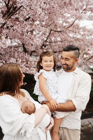 Family gathering under blooming cherry blossom trees in springtime.