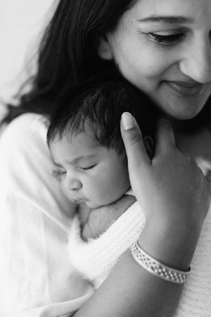 Series of black and white photos capturing gentle bonding moments with a sleeping infant.