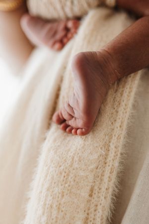 Close-up shots of a tiny baby's feet resting on soft white knitted fabric.