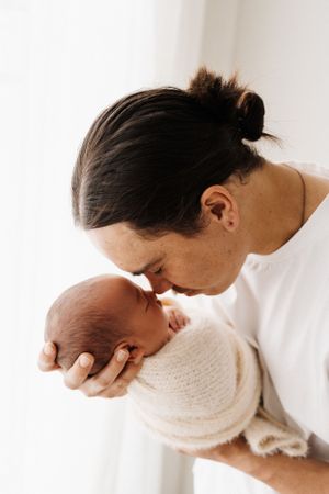 A series of artistic close-ups capturing intimate parent-child bonding moments in white tones.