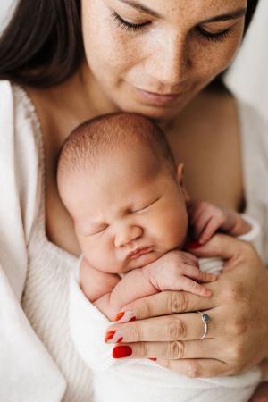Close-up series of tender moments showing hands gently touching a sleeping infant against a white background.