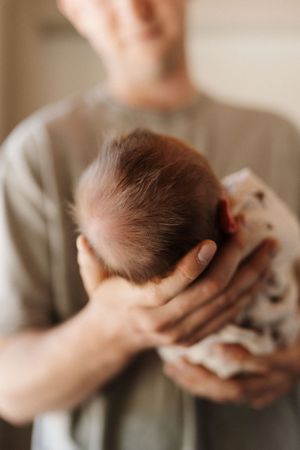 Close-up series showing gentle hands cradling newborn baby's head.