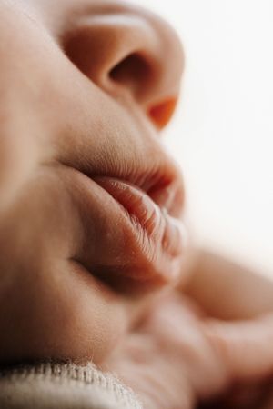 Close-up soft focus shot of a sleeping newborn's lips and nose showing delicate facial features in natural lighting.