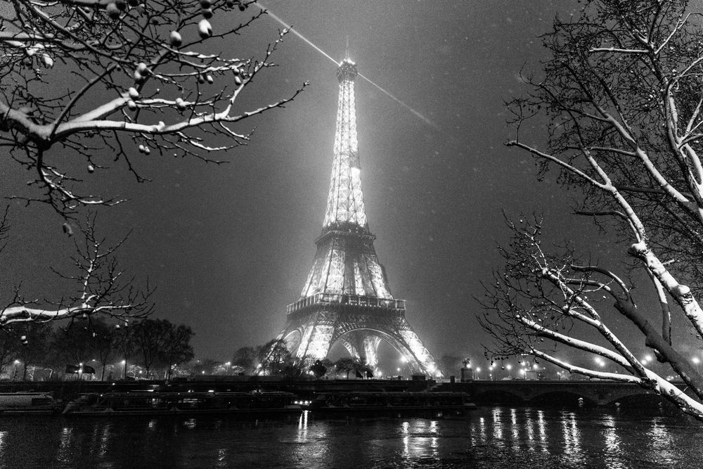 Black and white photo of the illuminated Eiffel Tower at night in winter, Paris, France.