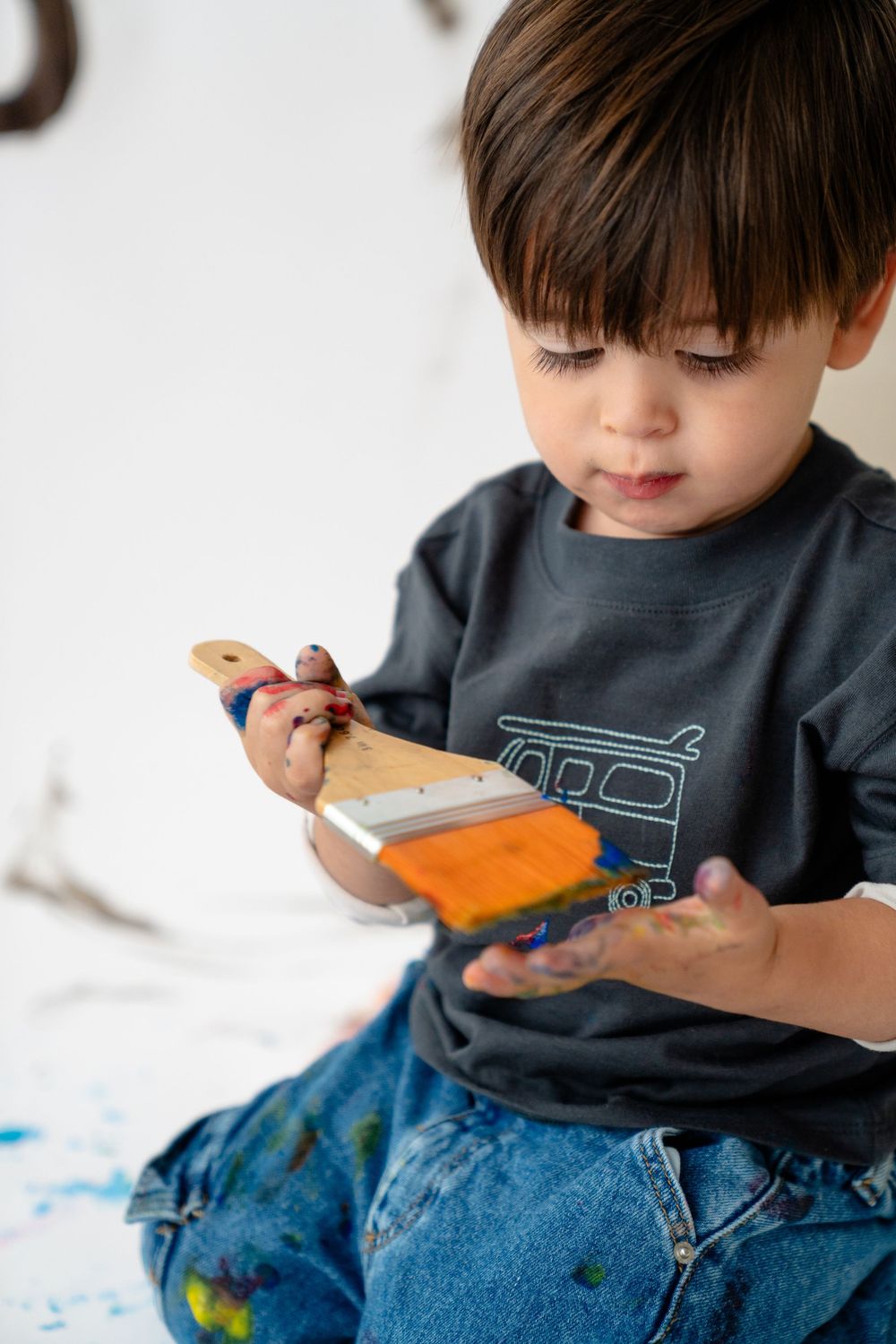A young child sitting on the floor, intently focused on playing with a toy or object.