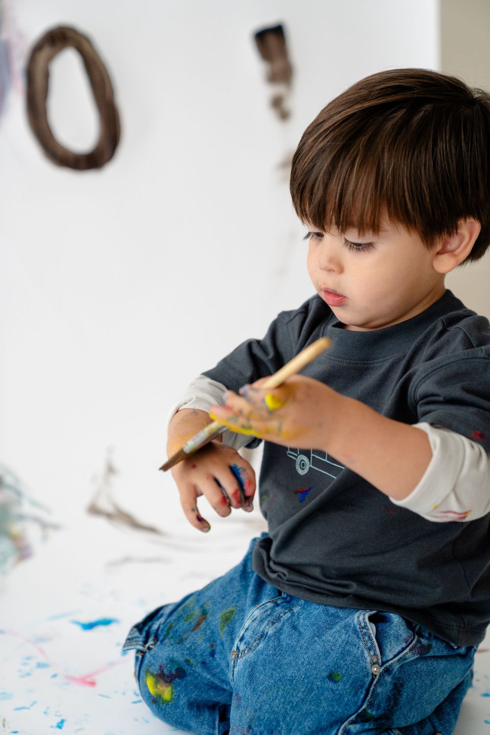 A young boy sitting on the floor, engrossed in playing with a toy.