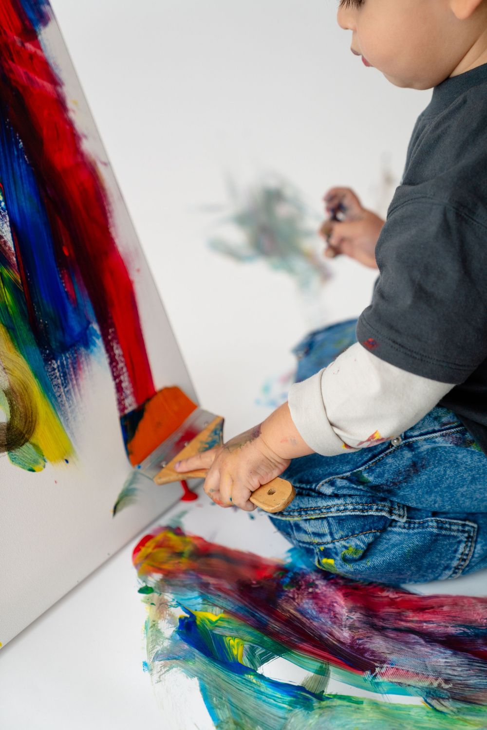 A person's hands are seen painting colorful strokes on a canvas in an artistic manner.