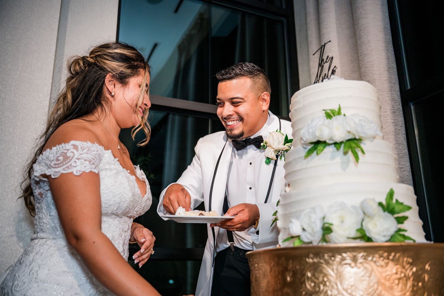 A bride and groom share an intimate moment while cutting their elegant white wedding cake together.