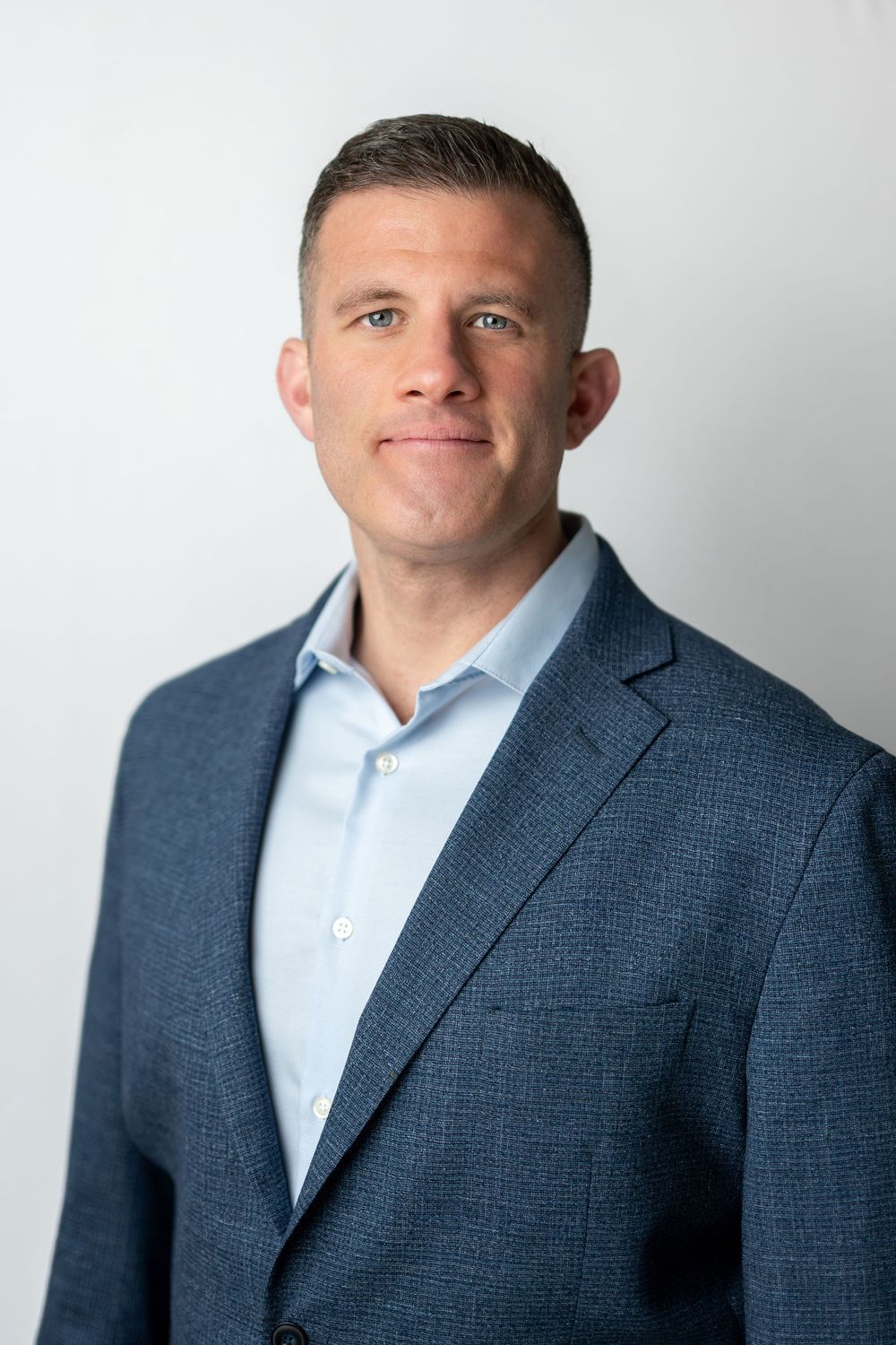 Professional headshot of a man in a blue blazer and light blue shirt against a clean white background.