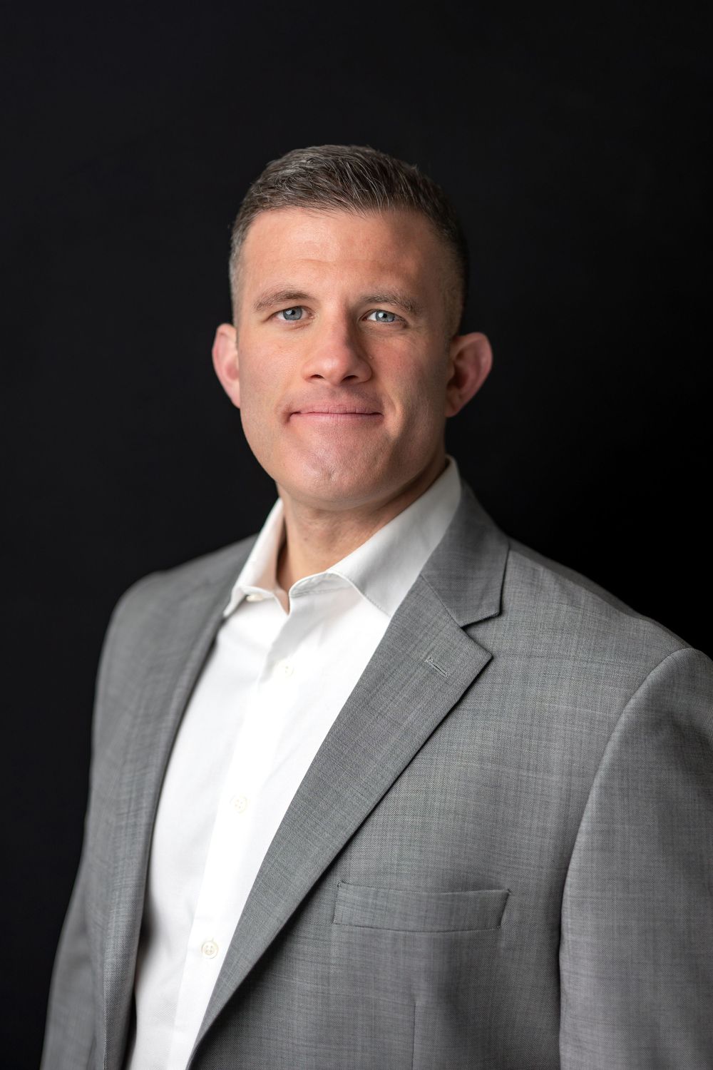 Business portrait of a man in a gray suit jacket and white shirt with a neutral expression.