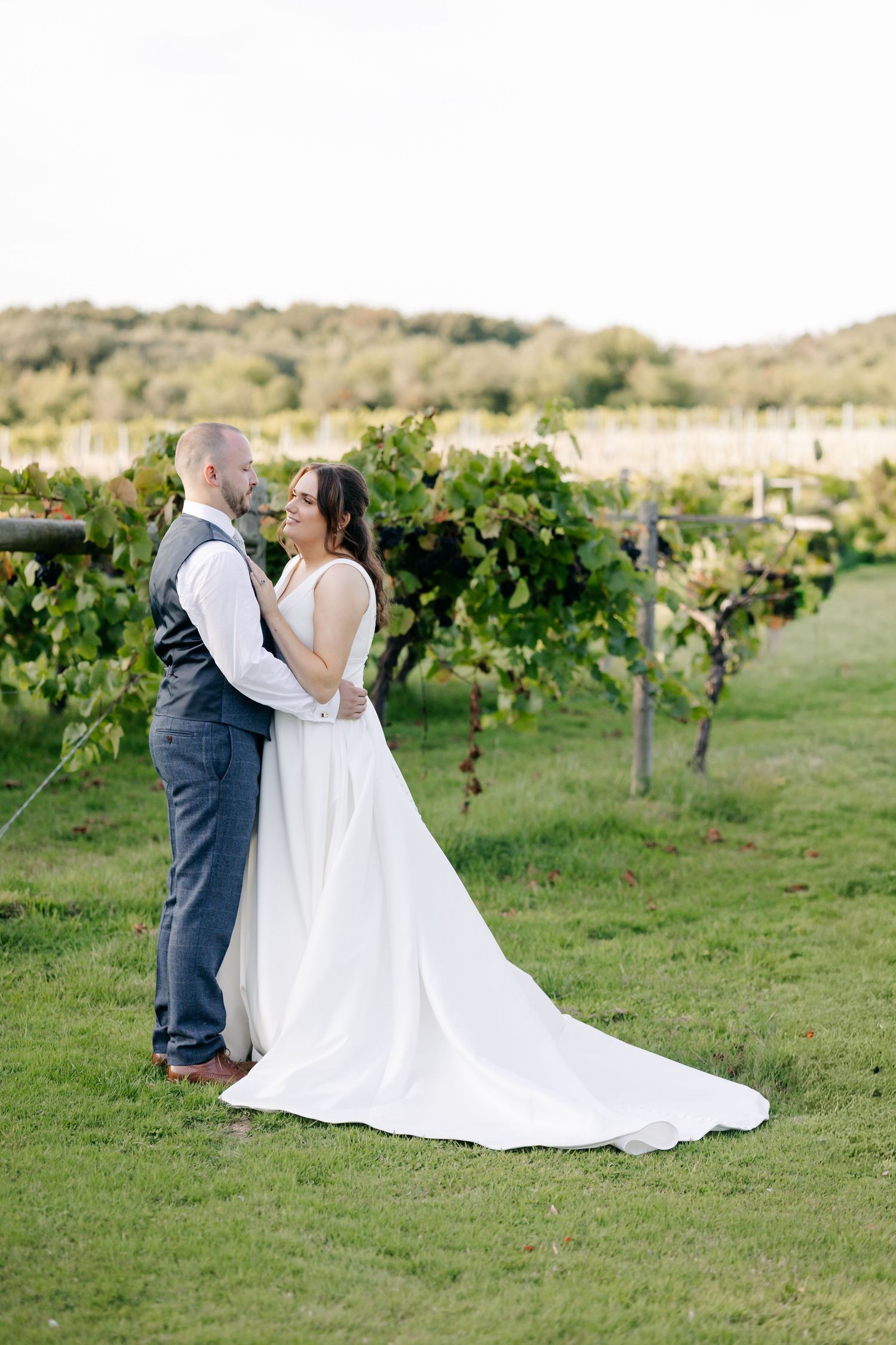 A couple shares an intimate moment in a scenic vineyard setting during their wedding photoshoot.