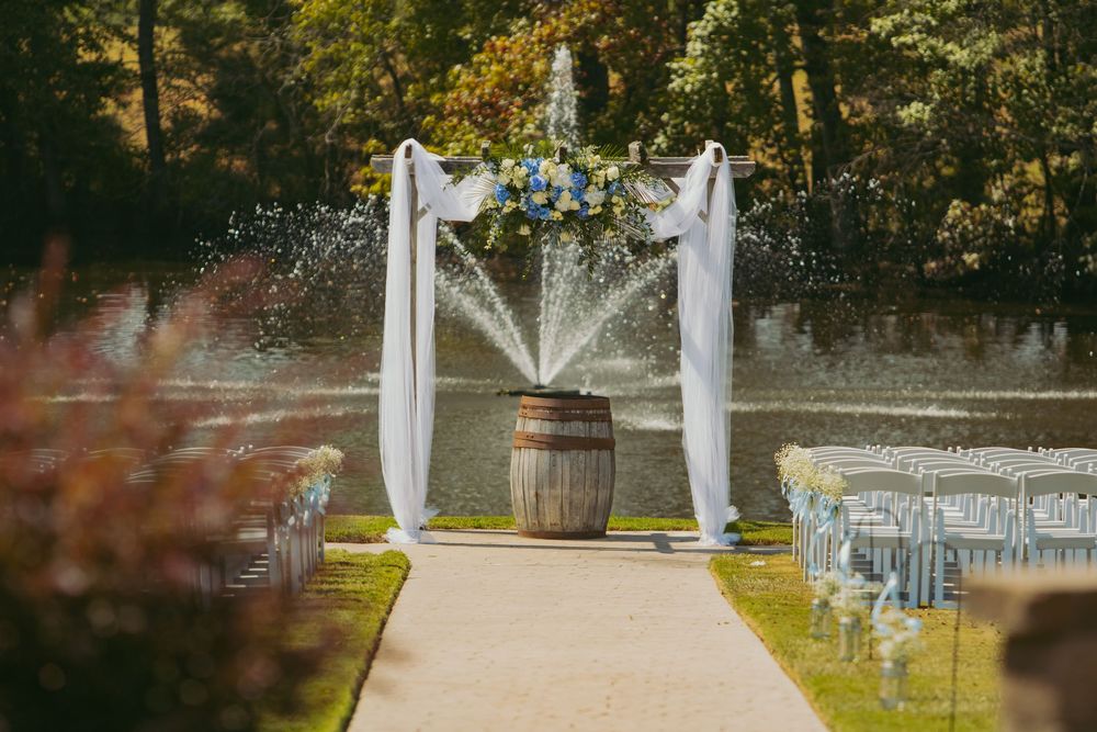 Elegant outdoor wedding ceremony setup with white draping and chairs arranged in rows on a grassy lawn.