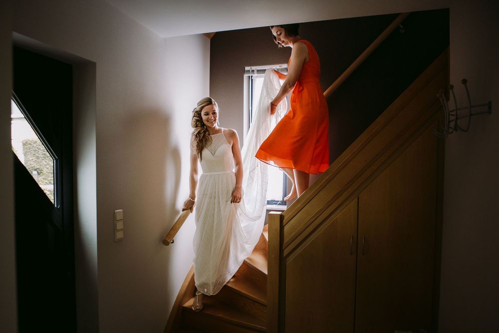 A person in a flowing white dress stands in a dark hallway with dramatic lighting and shadows.