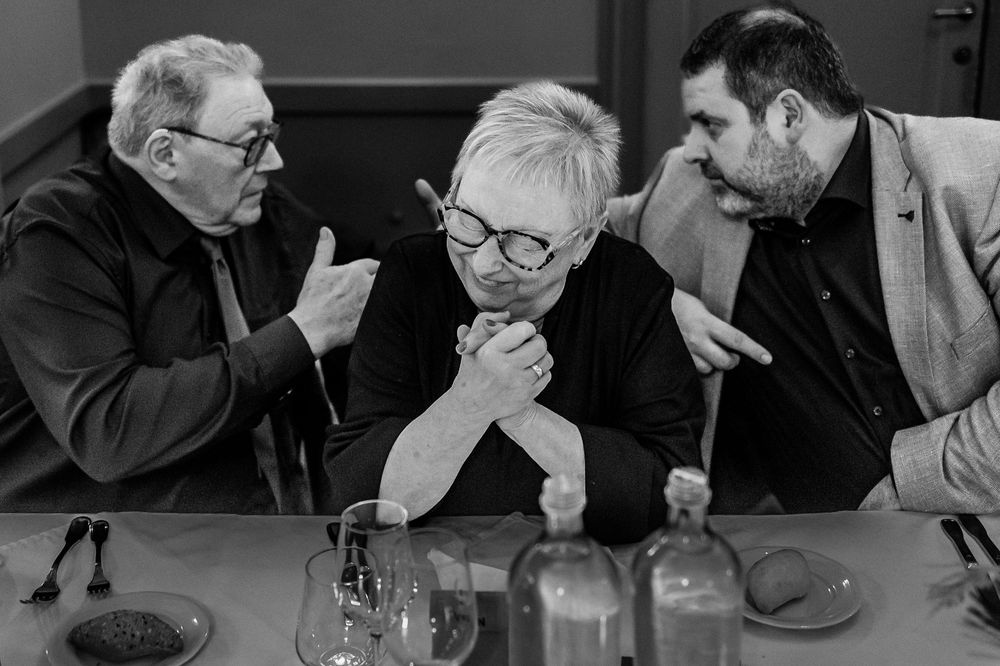 A black and white photo series showing people engaged in thoughtful discussion around a table.