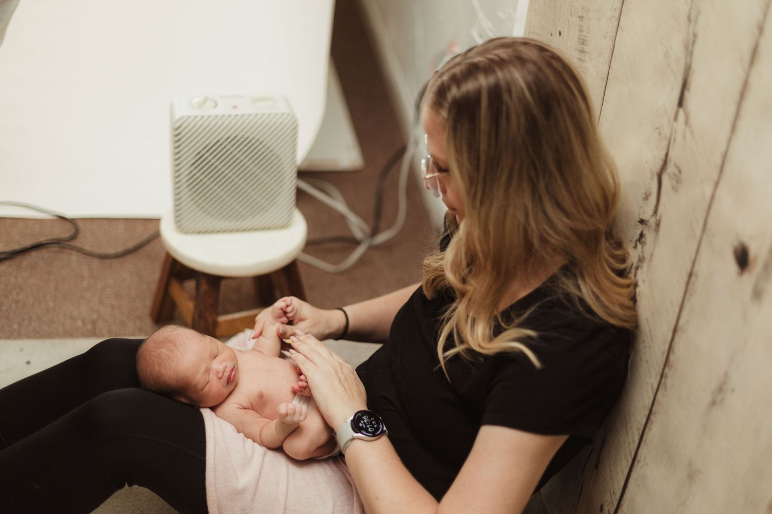 Professional photographer tenderly captures intimate newborn portrait session in natural light setting.