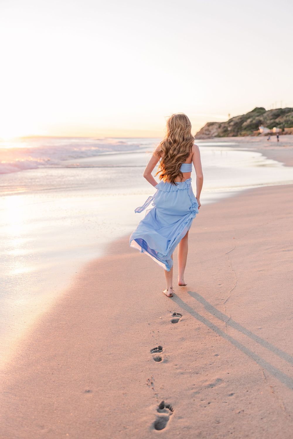 A series of five connected photos showing a person walking and leaving footprints on a pink-tinted sandy beach at sunset.