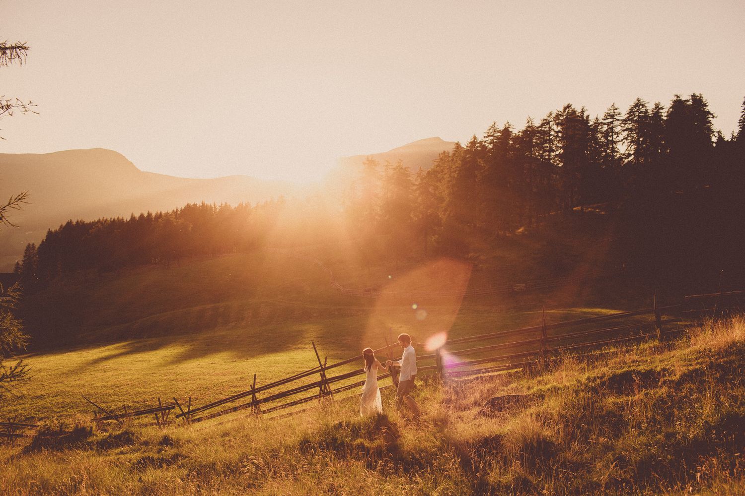 Dolomites wedding couple walking through alpine meadow at sunset