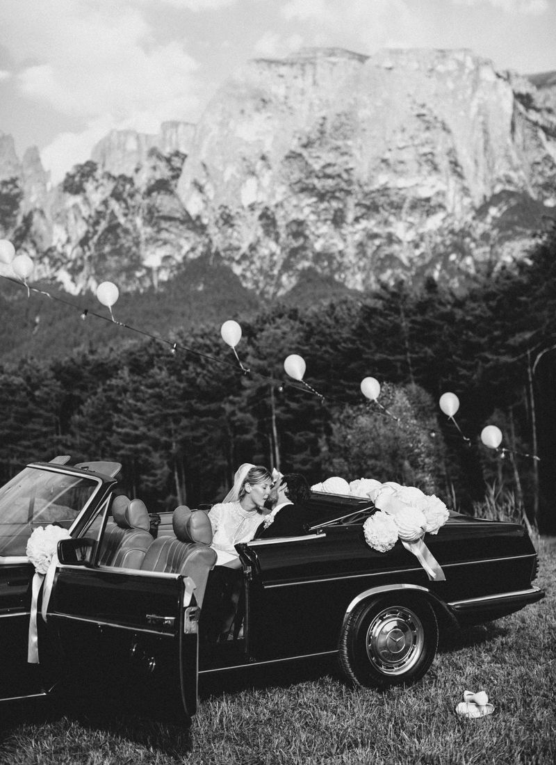 Bride and groom arriving in vintage car during destination wedding in the Dolomites