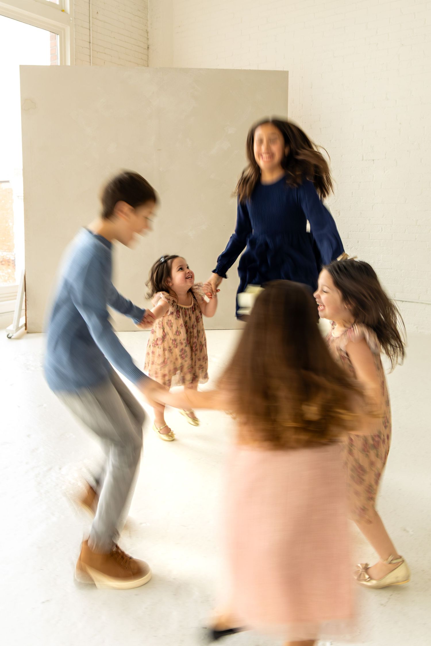Motion blur captures dancers in a bright studio space creating dynamic movement and energy during a performance.
