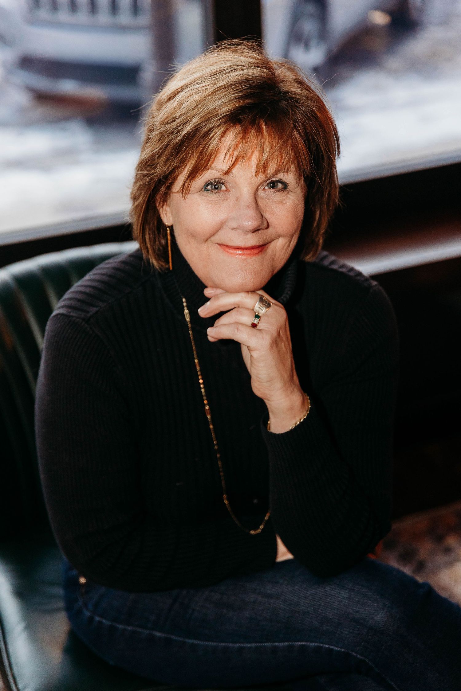 A woman in a black turtleneck sweater poses thoughtfully in a series of four similar portrait photographs.