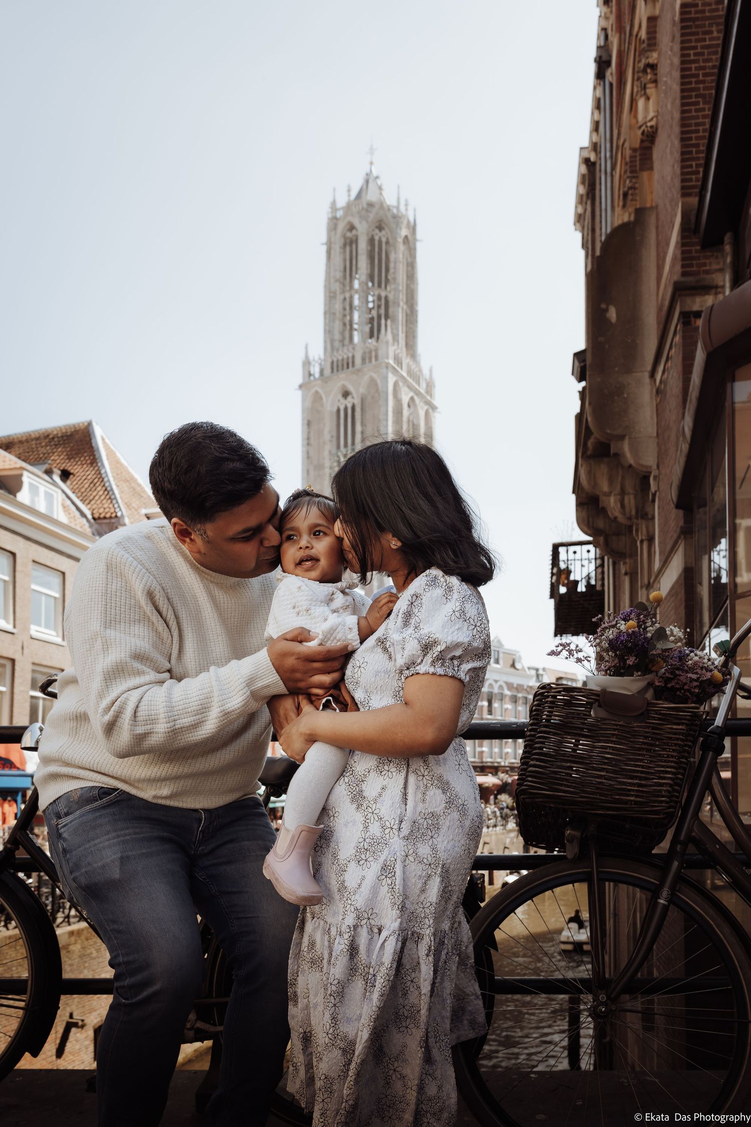 Family sharing a tender moment on a Utrecht bridge with the iconic Dom Tower in the background.