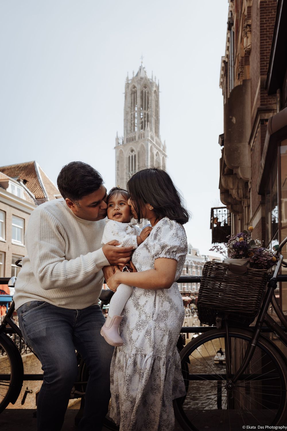 Family sharing a tender moment on a Utrecht bridge with the iconic Dom Tower in the background.