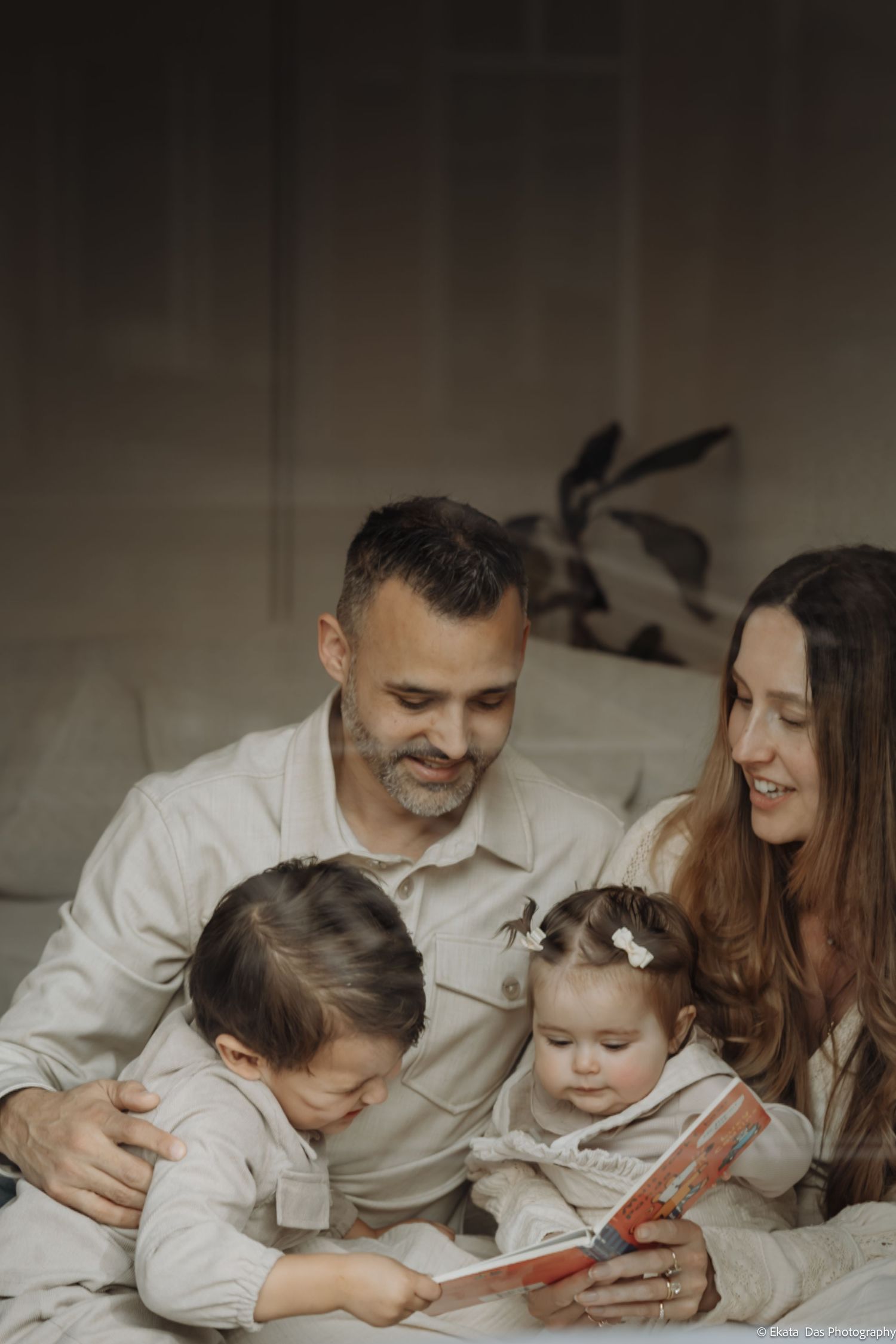Family reading together while lying on a cozy bed.