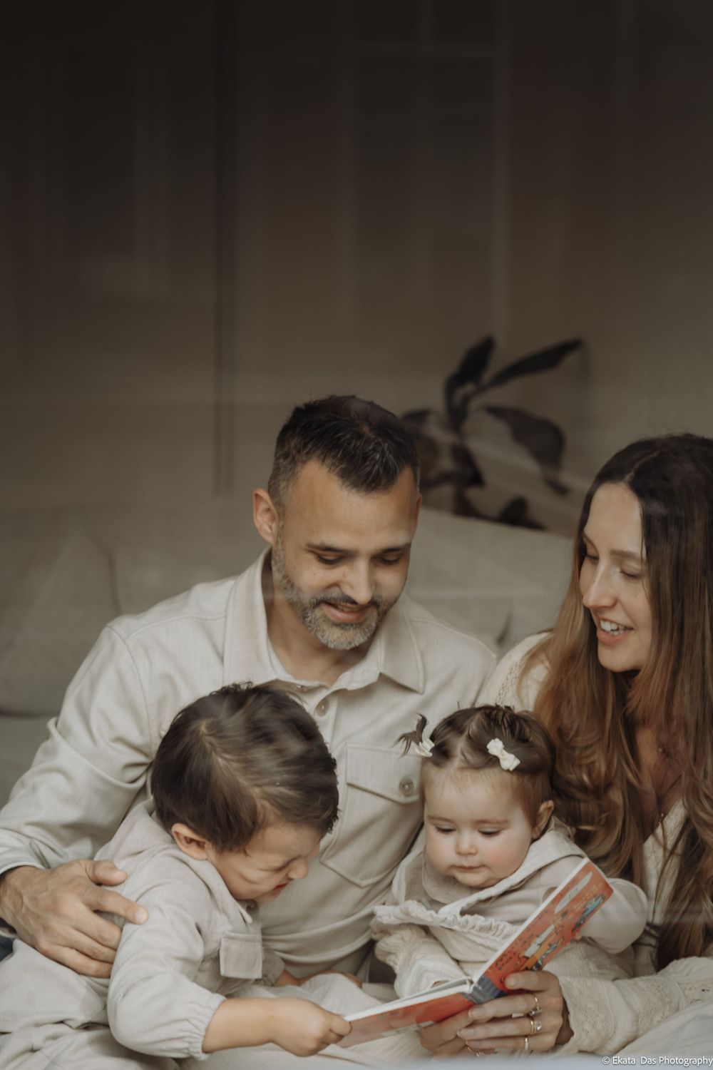 Family reading together while lying on a cozy bed.