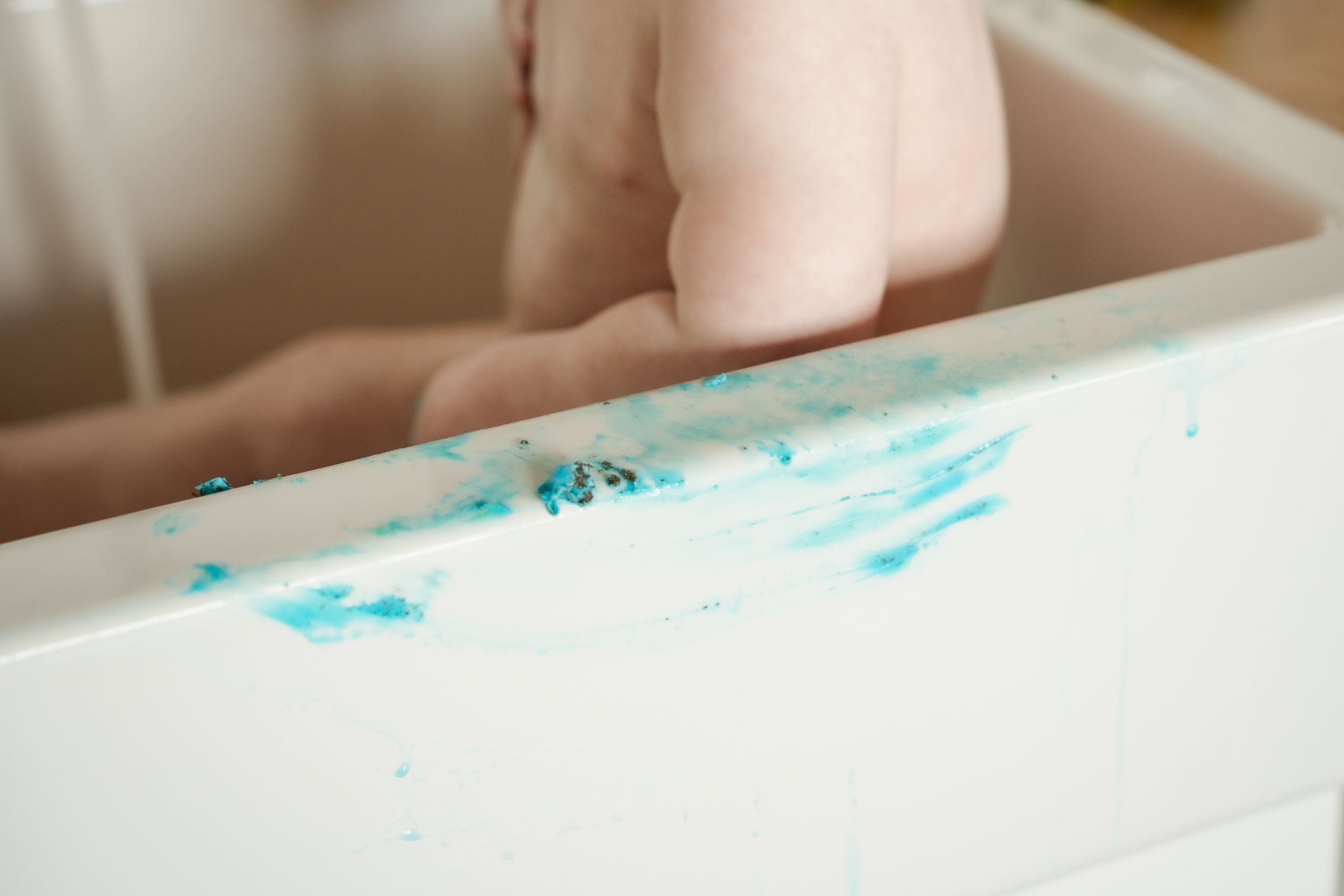 Multiple shots show a baby exploring blue frosting or paint while sitting in a kitchen sink.