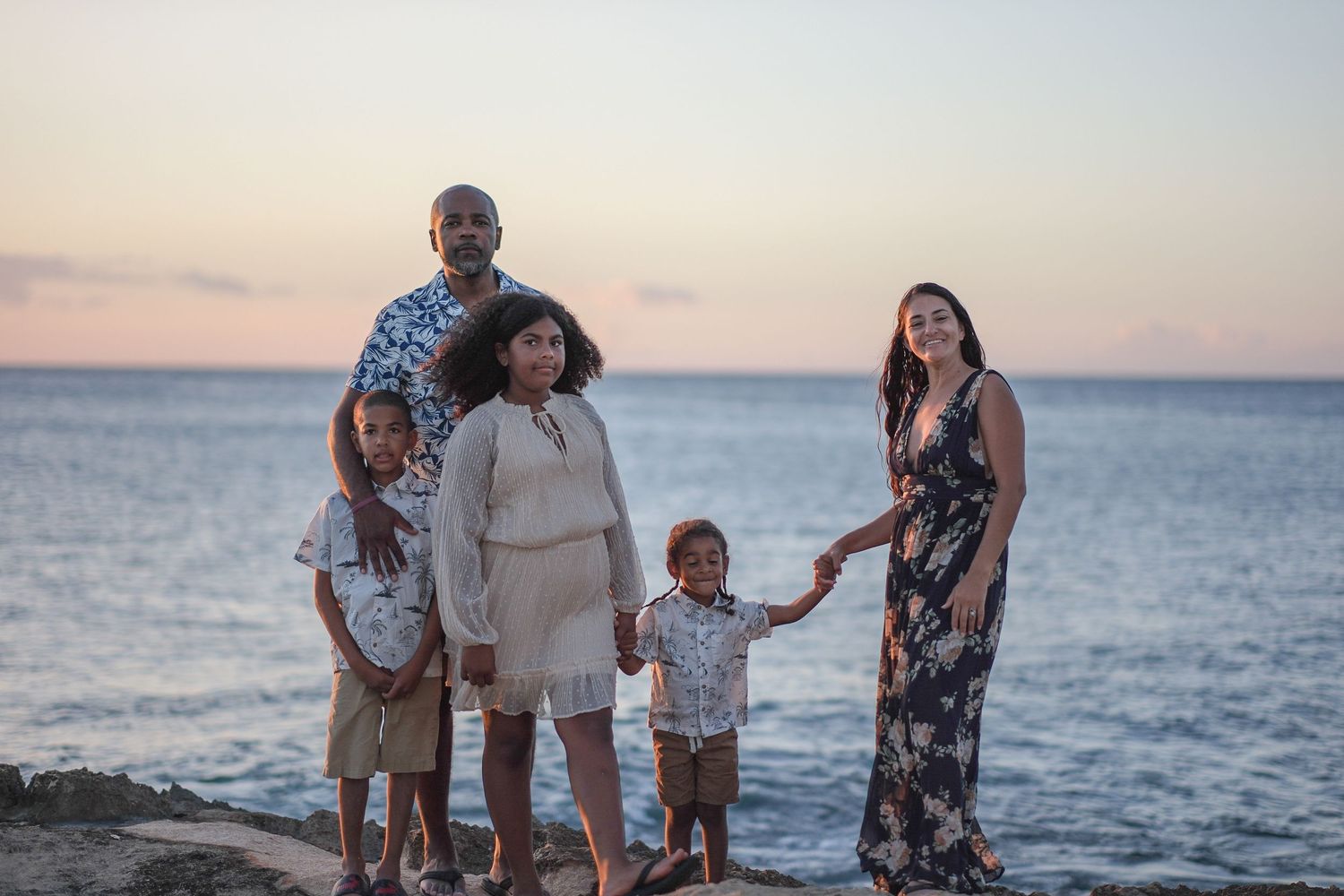 Family gathered along the shoreline during a North Shore Oahu family photography session at sunset.