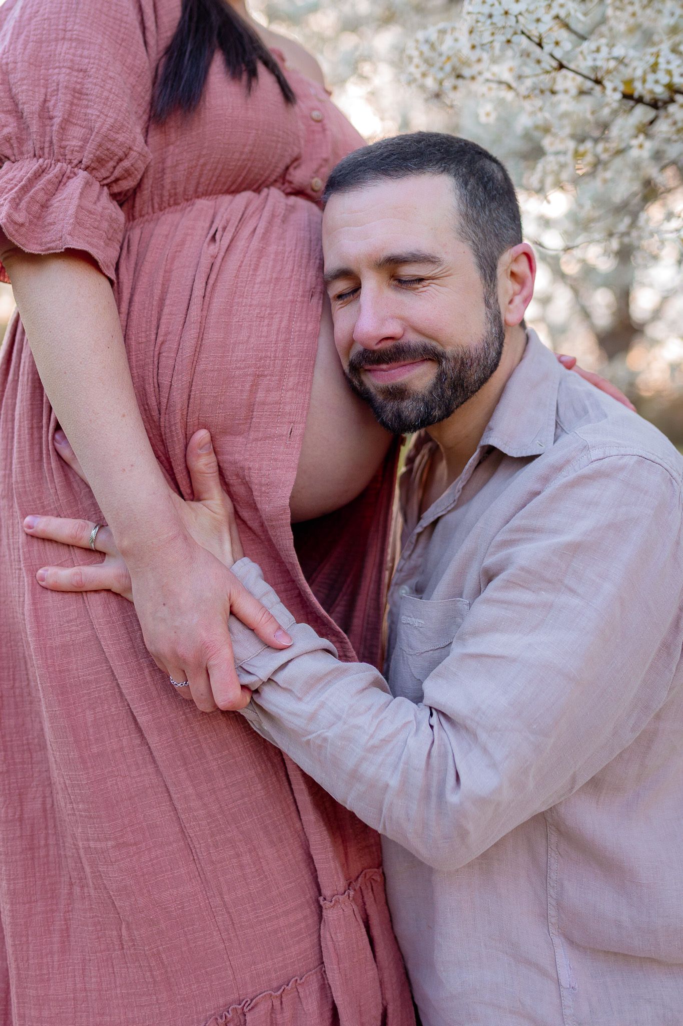 Papa posant sa tête contre le ventre de la future maman avec émotion