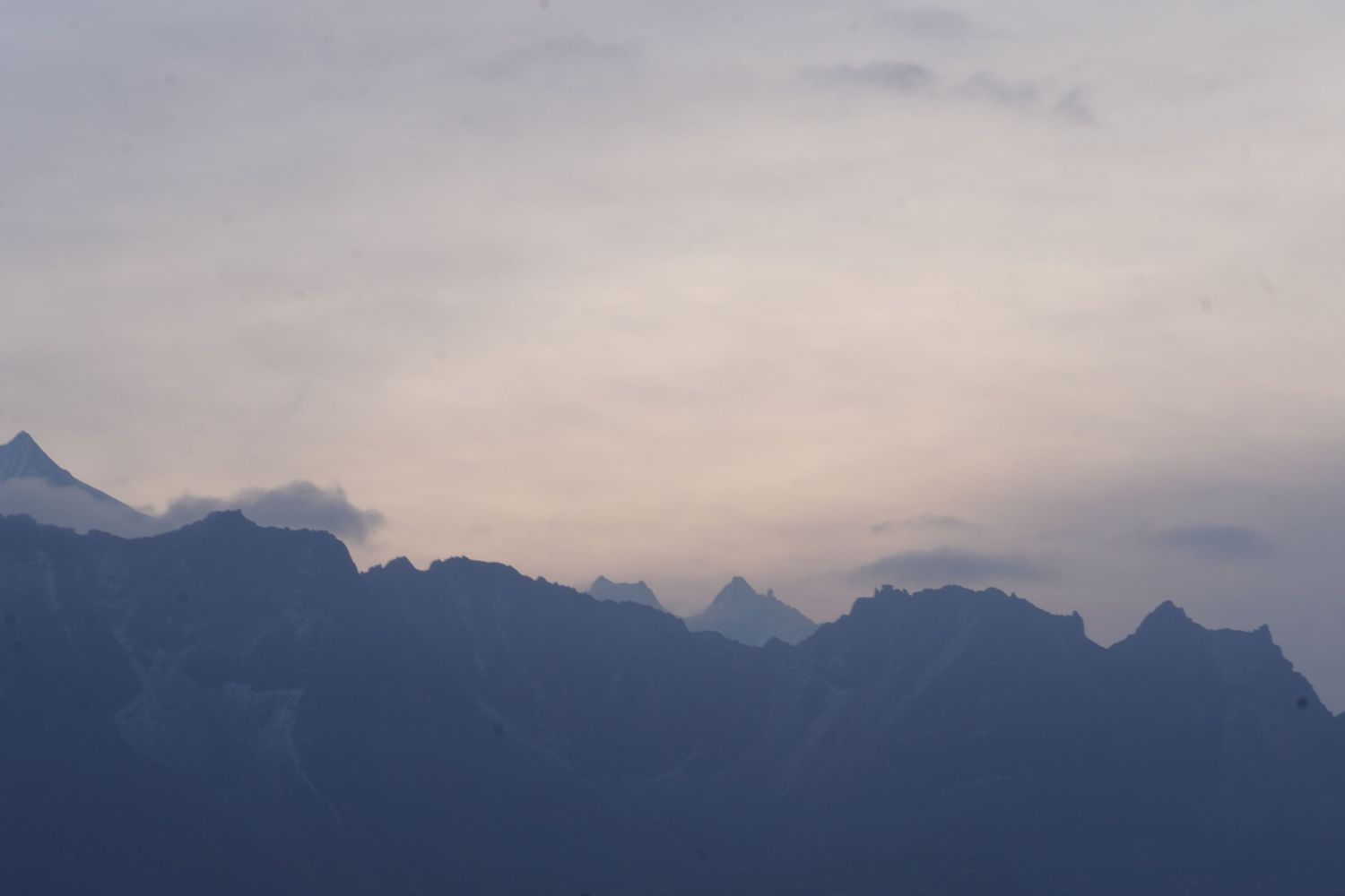 Layered silhouettes of mountain ranges at dusk, showcasing the atmospheric silence of the Himalayan peaks.