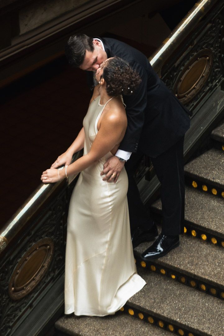 A bride and groom share an intimate kiss on the stairs at the Cleveland Arcade during their wedding ceremony.