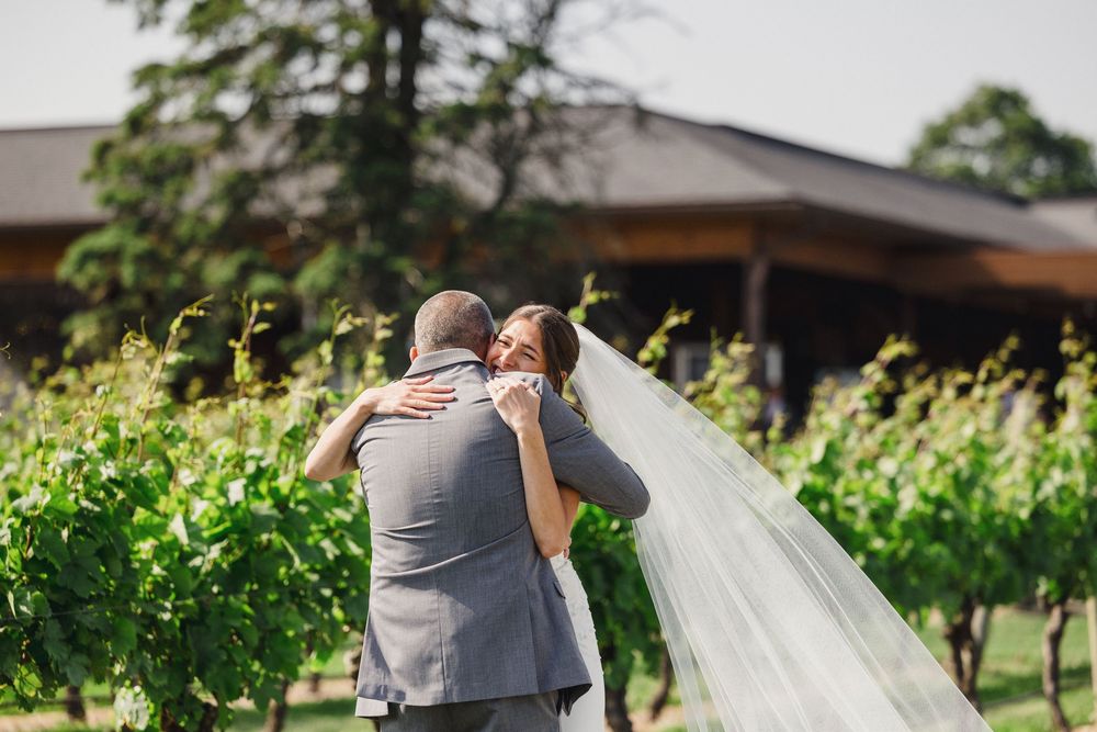Newlyweds share intimate moments in vineyard setting with flowing veil.