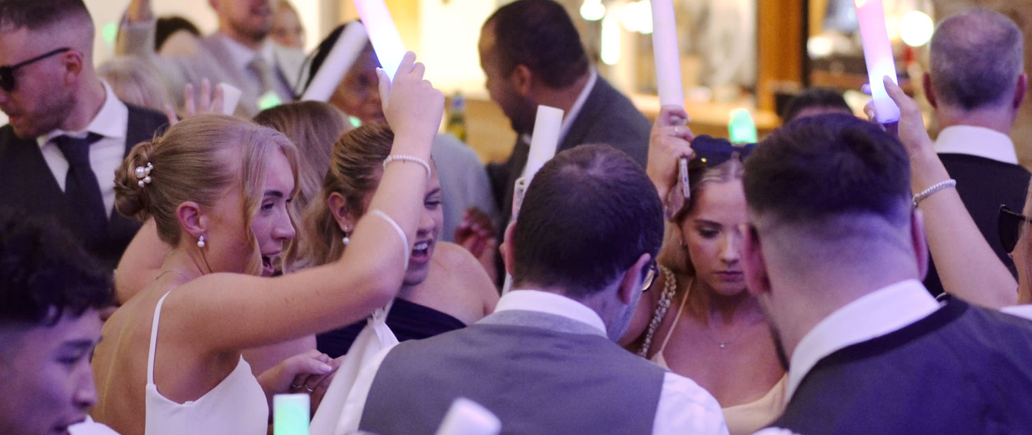 Wedding reception dance floor with purple mood lighting and celebrating guests.