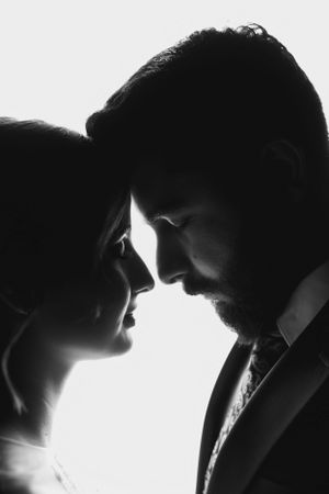A dramatic black and white silhouette portrait of a couple in formal attire.