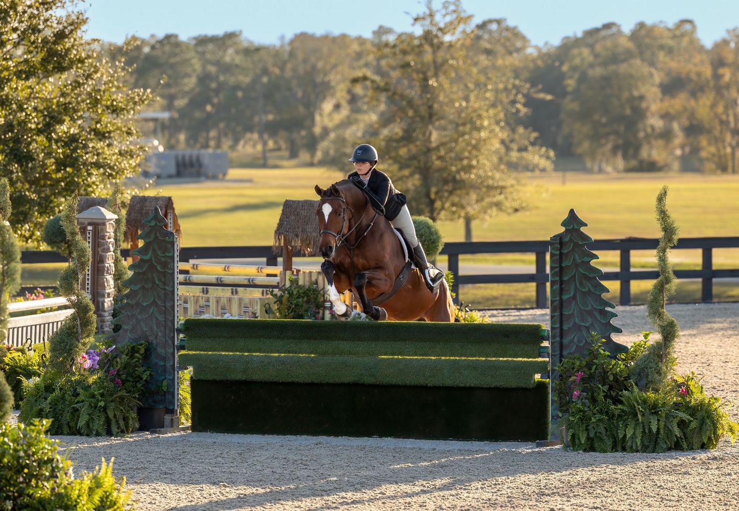 Equestrian and horse jumping over obstacle at outdoor competition course.