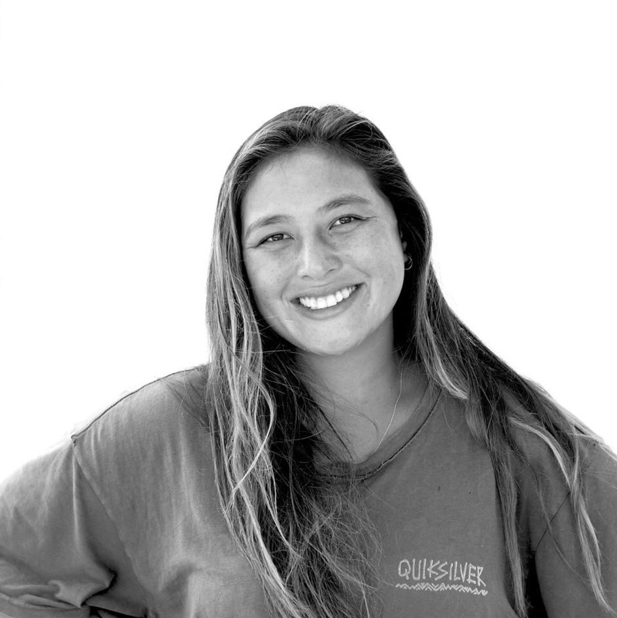 Black and white portrait of someone with long dark hair smiling while wearing a crew neck sweatshirt.