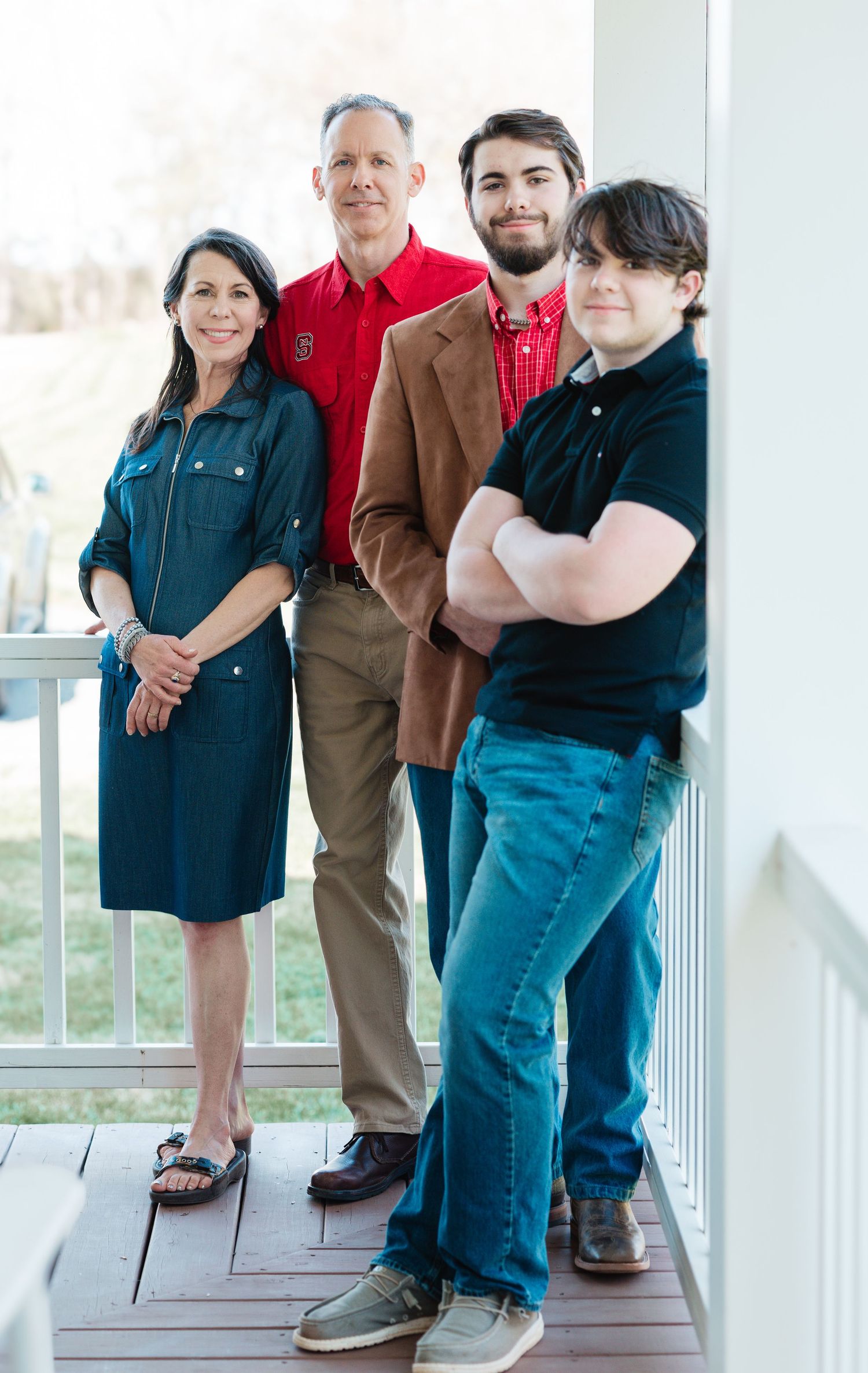 Family portrait of four people on a deck wearing casual and business attire.