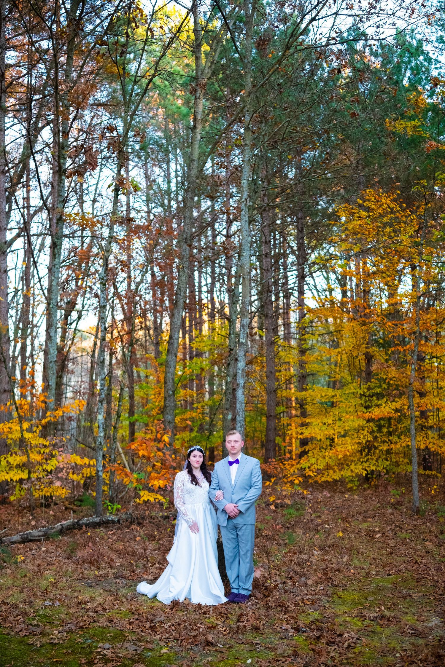 Connor with his new wife Taylor stand together in a colorful fall forest.