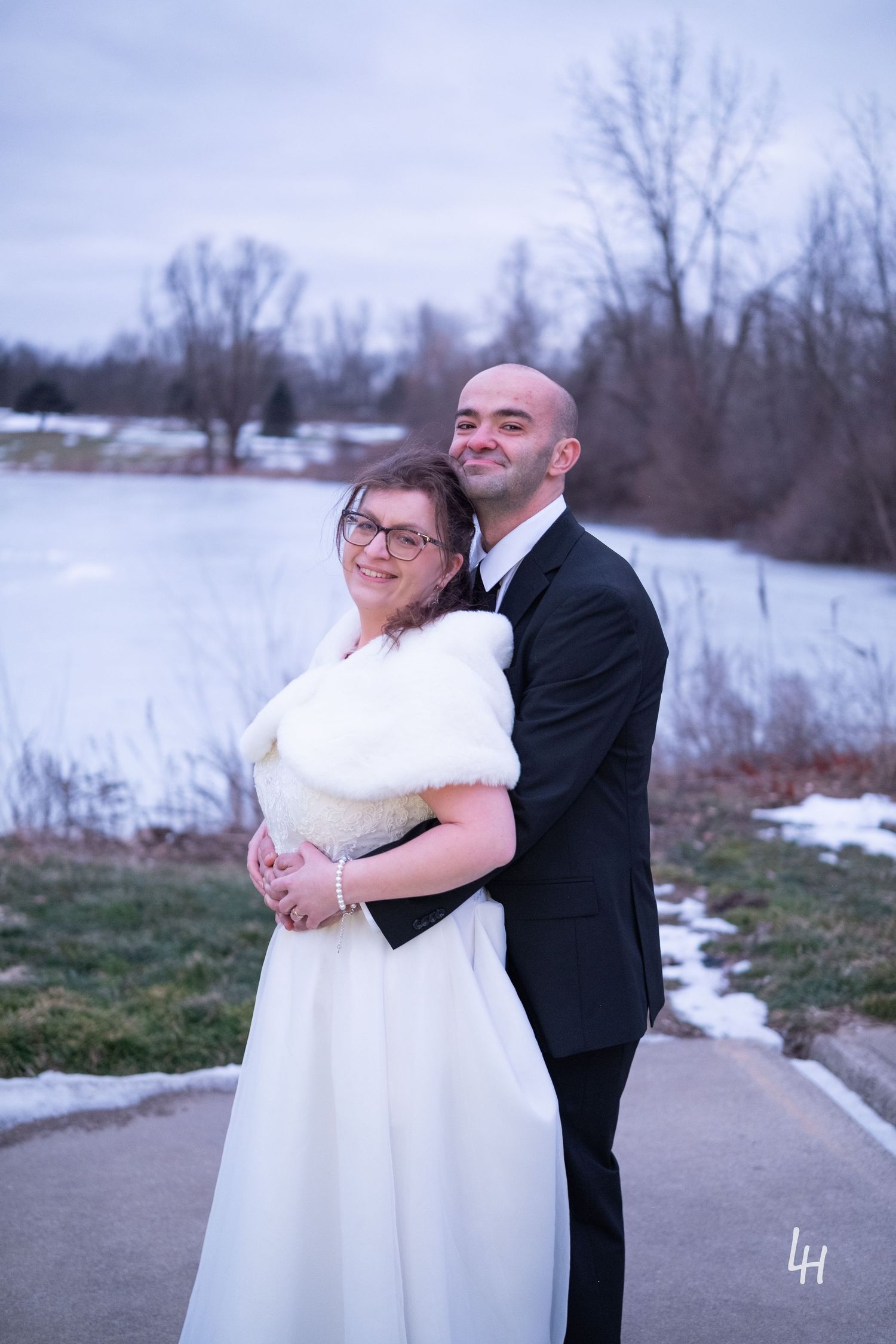 Kevin holding Jamie's waist from behind in front of a frozen lake.