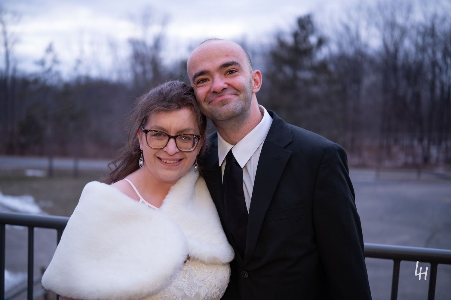 Kevin leaning his head on Jamie's with a wintery forest in the background after their wedding.