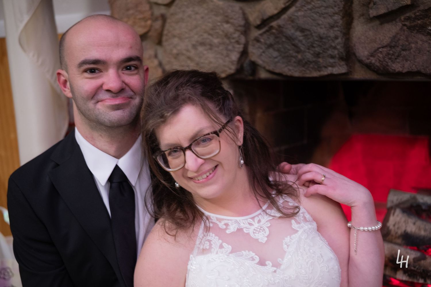 Jamie leans on Kevin's shoulder in front of a fireplace.