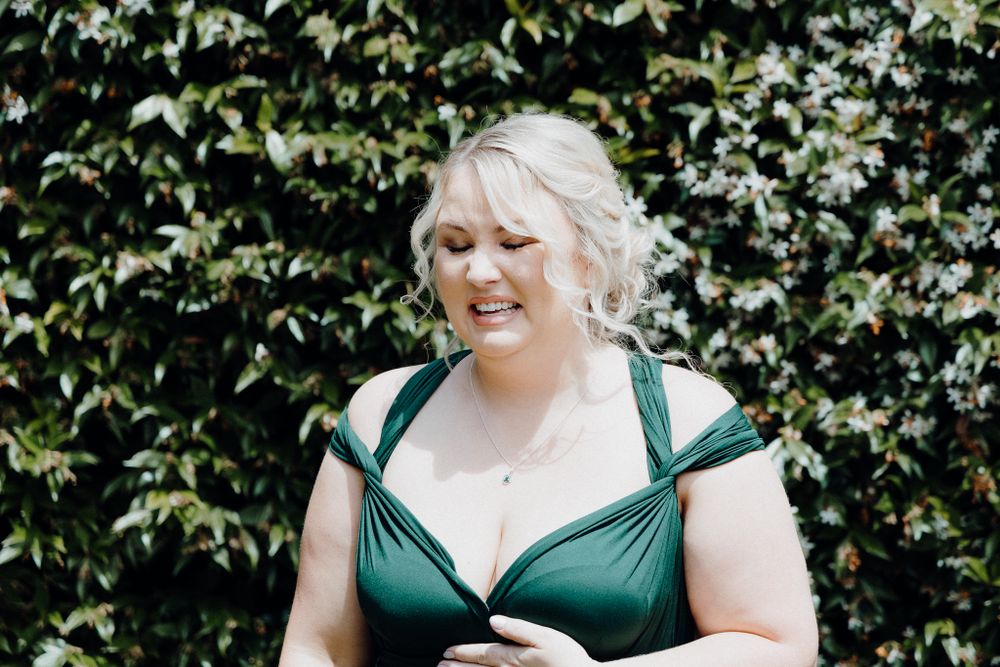 The Bridesmaid in an emerald green dress smiles warmly as she sees the bride, captured by Apertured Media Auckland Wedding Photographer.