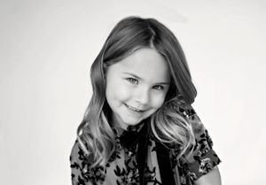 A black and white portrait featuring long wavy hair and a patterned dark top.