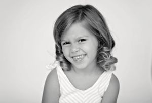 A black and white portrait capturing a joyful expression with curled hair.